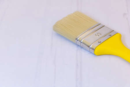 A new paint brush with the yellow handle on gray background with copy space.