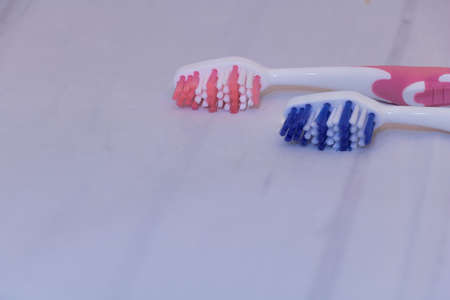 Two toothbrushes close up - one blue and one pink with on gray surface with copy space.