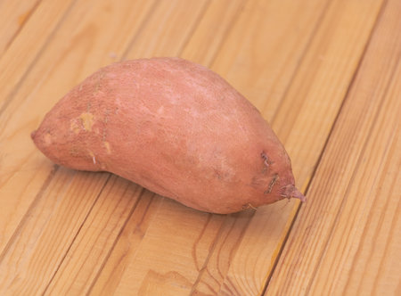 One fresh sweet potato on wooden background - Benefits of sweet potatoes concept.の写真素材