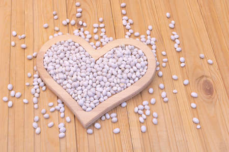 Close up shot of white beans raw in a heart-shaped plate.