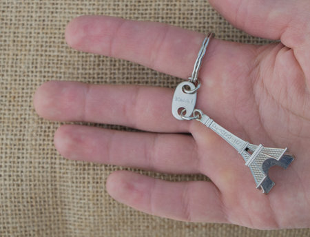Hand holding a key with Eiffel Tower in the background.の写真素材