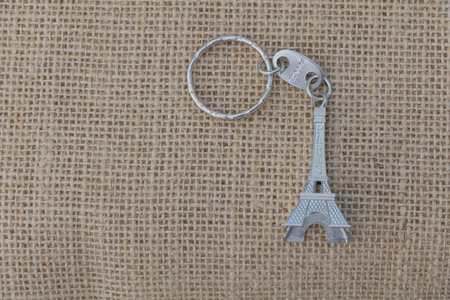 Eiffel Tower key on sackcloth background with copy space.