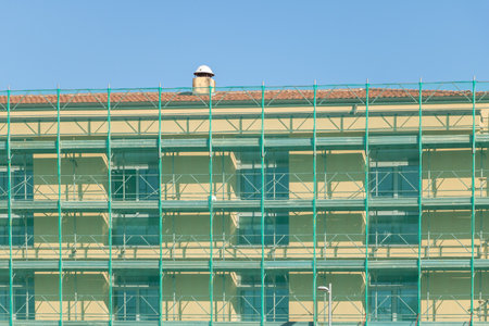 Facade of a building under construction with scaffolding against blue sky.の写真素材