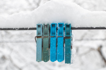 Close-up of pins covered in snow on a line, winter background, blue and green colored.の写真素材