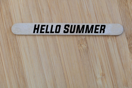 A wooden popsicle stick with the text Hello summer. Concept for summer season.