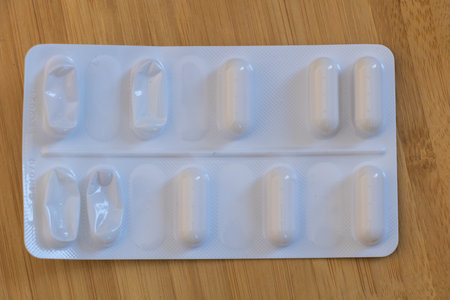 Partially Empty Blister Pack of White Capsules on Wooden Surface.