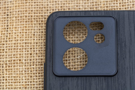 A black plastic phone case with three round holes on the front, showing its camera lens and screen,...