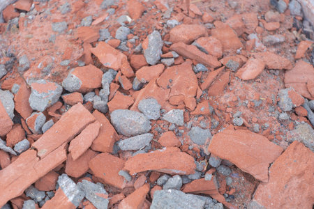 Close-up of red and gray bricks, debris scattered on the ground, construction site background.