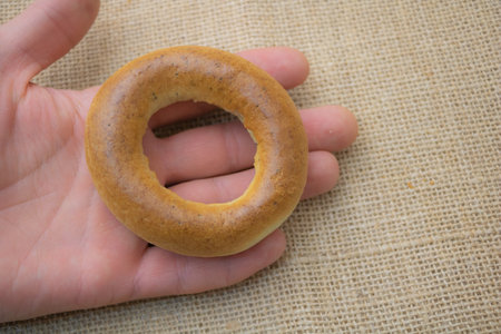 Hand Holding Freshly Baked Bagel on Burlap Fabric