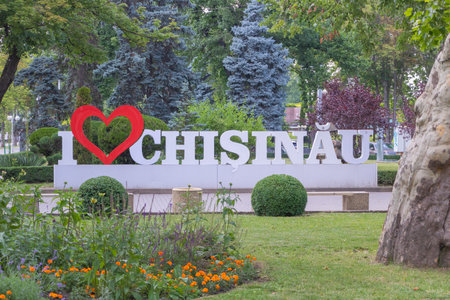 A large white inscription I love Chisinau with red heart-shaped letters stands in the city park, surrounded by greenery and flowers in Chisinau.の写真素材