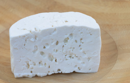 Fresh White Cheese Block on Wooden Plate Closeup.の写真素材