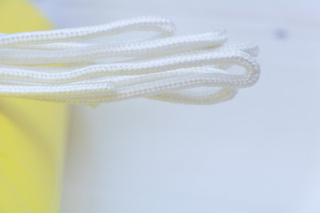 Closeup of white braided textile cord or shoelace on light background, detailed macro texture for...