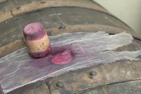 Wine barrel stopper with red wine stains on wooden cask and mesh cloth, traditional winemaking...