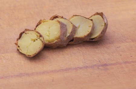 Sliced boiled potato on wooden cutting board.の写真素材