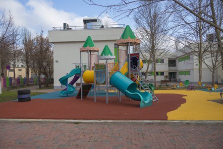 Colorful children playground with slides, climbing frames, tunnels, ladders, and safety flooring in...