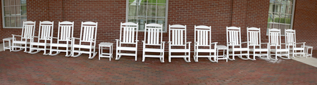 Panorama of white rocking chairs on brick patio.の写真素材