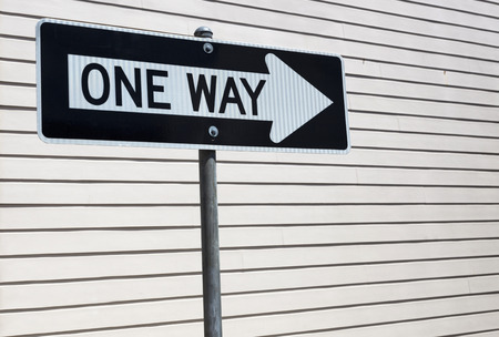 ONE WAY sign with light beige clapboard wall background. Horizontal.の写真素材