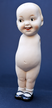 Naked ceramic doll with no arms, but wearing an upbeat smile. Vertical.の写真素材
