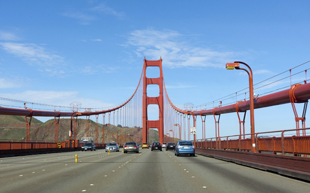 Fog and blue sky as traffic crosses the Golden Gate Bridge.