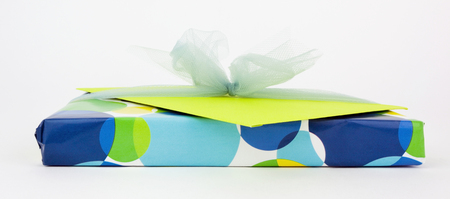 Blue, yellow, and green gift with bow and card. Isolated.