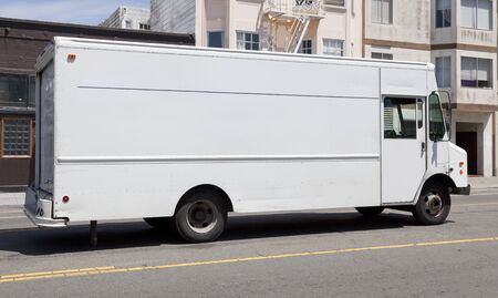 Side view of parked white delivery truck on urban street.