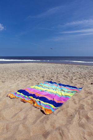 Colorful beach towel on sand with ocean and sky background. Vertical.の写真素材
