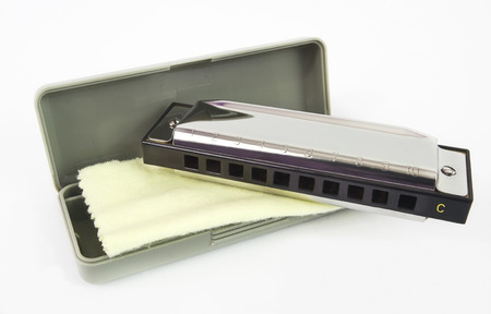Shiny harmonica with carrying case and cloth. Isolated.