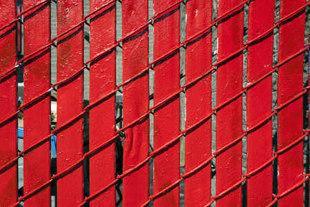 Detail close up of bright red wood slats and chain link fence.の写真素材