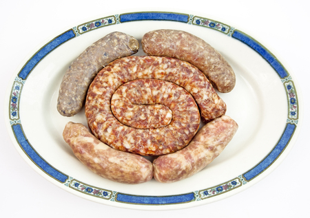 Plate filled with assorted types of raw sausages. Isolated.の写真素材