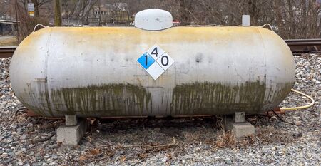 Large grungy weathered propane liquid gas tank on cement blocks.の写真素材
