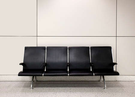 Empty black airport seats against wall.の写真素材