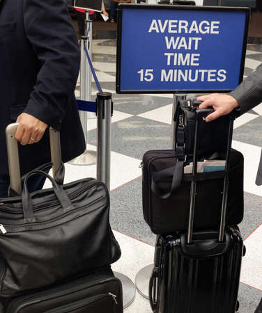Business passengers with luggage waiting to board in airport queue.