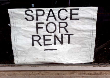 Unappealing SPACE FOR RENT sign posted inside dirty window.の写真素材
