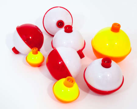 Red and white and yellow, orange day-glo fishing bobbers on a white background.の写真素材
