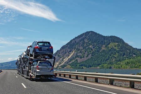 Flipped image. Car cargo to destination. New vehicles transported to dealerships along on highway along river.の写真素材