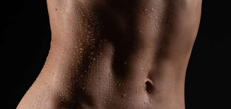 Close up of fit woman torso with sweat on skin after workout. Female with perfect abdomen musclesの写真素材