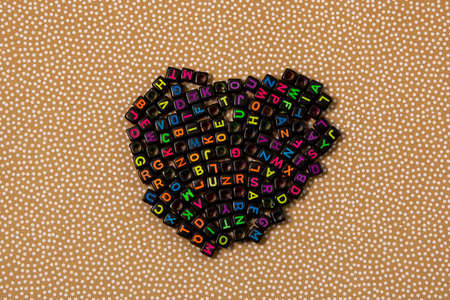 Multicolored plastic cube beads with letters scattered. background texture.の写真素材