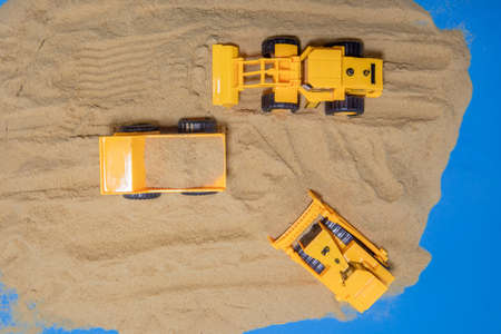 Big excavator is filling a dumper truck with soil at construction site, project in progress.の写真素材