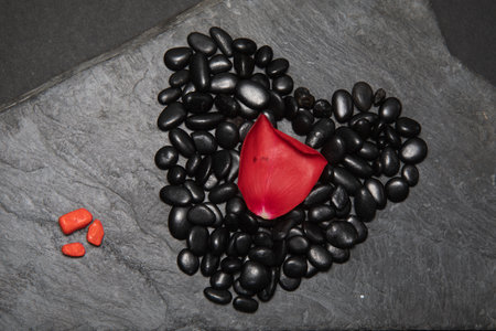 Black stones with black zen heart shaped rock on grain sand . High quality photoの写真素材