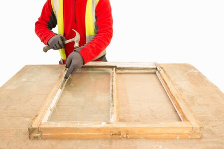 Carpenter using a hammer while repairing and restoring an old window frame sash. Sash window...