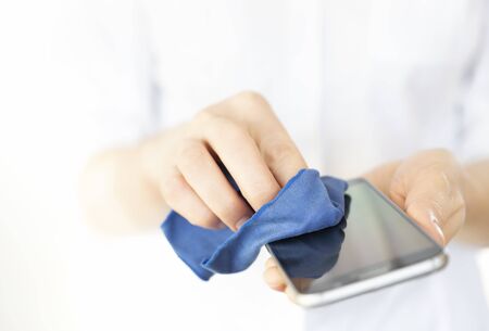 A person cleaning mobile phone to prevent the spread of germs, bacteria and corona virus.