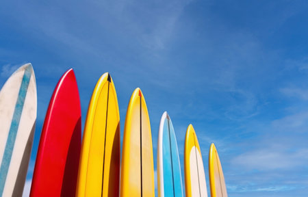 Set of differently colored surfboards stacked by the ocean.の素材