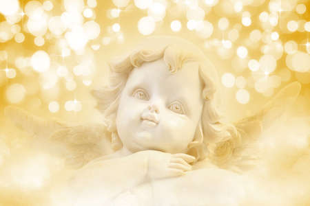 Christmas Angel a background of golden holiday lightsの写真素材