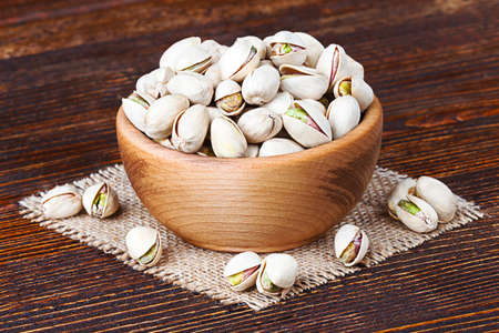 Pistachios in wooden bowl over wooden background(selective focus).の写真素材