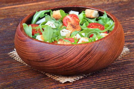 Fresh salad with rucola, tomato, cheese and toast bread on an old brown wooden table(selective focus).の写真素材