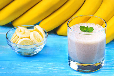 Banana smoothie on a blue wooden table(selective focus).の写真素材