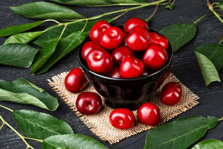 Fresh cherries in bowl on old black wooden table(selective focus).