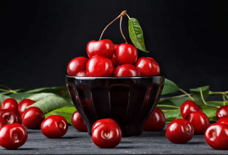 Fresh cherries in bowl on old black wooden table(selective focus).の写真素材