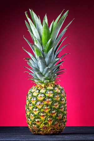 Fresh pineapple tropical fruit (ananas).Summer fruit on a black wooden table over pink background(selective focus).の写真素材