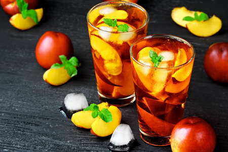 Peach ice tea in a glass with mint on a black wooden table(selective focus).の写真素材